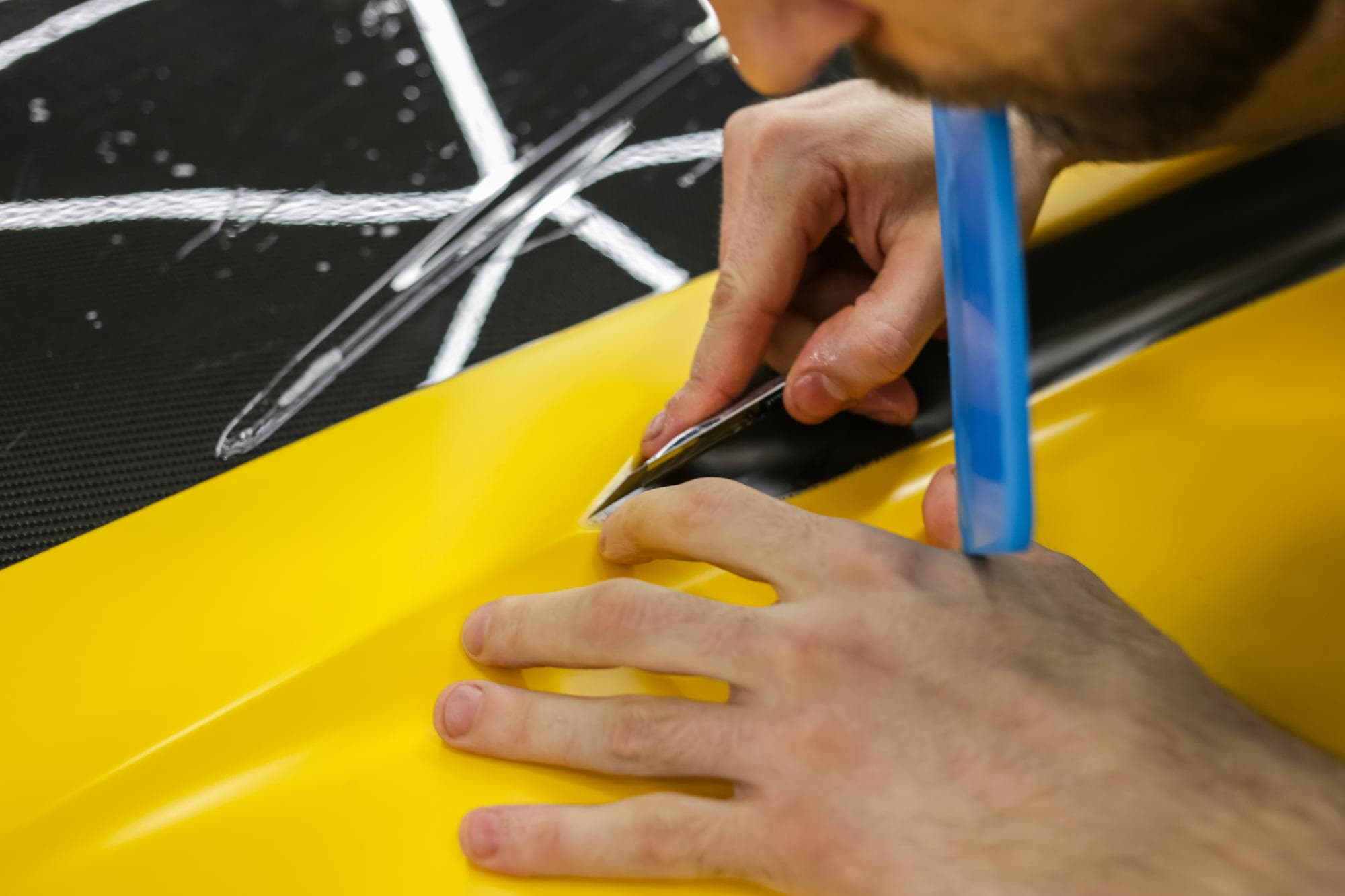Colored vinyl wrap being applied to a car panel